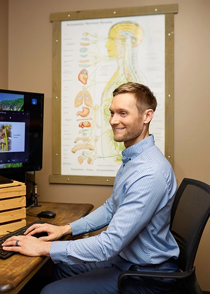 Chiropractor Lino Lakes MN Tyler Hanson Smiling At His Desk